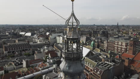 Circular-drone-shot-of-the-Bell-Tower-of-The-Old-Church-with-cityscape-of-Amsterdam-in-The-Netherlands