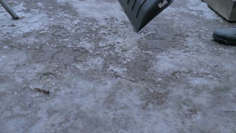 Street-cleaner-woks-with-shovel-to-remove-snow-and-ice-from-road,-ta-make-it-safe-for-walking