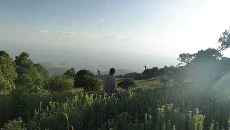 A-western-man-who-is-hiking-looks-over-an-East-African-valley-towards-Kenya