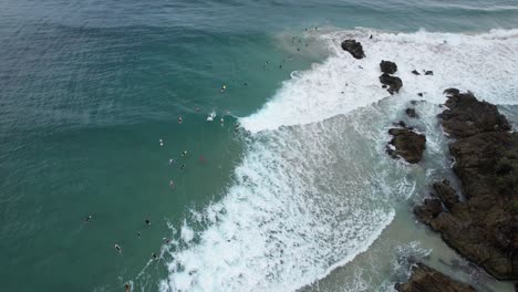 Waves-And-Surfers-Enjoying-At-The-Pass-Beach-In-Byron-Bay,-NSW,-Australia---Aerial-Drone-Shot