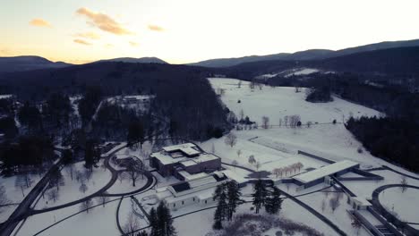 Golden-sunsetting-sky-over-Clark-art-institute-with-rolling-snow-covered-hills-and-evergreen-forests-in-Williamstown,-Massachusetts,-USA