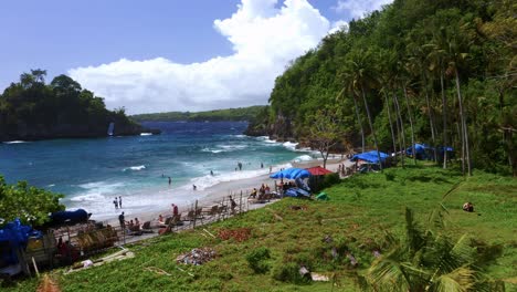 Vista-Aérea-Baja-De-Turistas-Tomando-El-Sol-Y-Nadando-En-La-Playa-De-Crystal-Bay-En-Nusa-Penida---Bali,-Indonesia