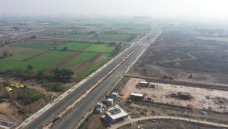 Rajkot-Atal-Lake-Vista-De-Drones-Cámara-De-Drones-Avanzando-Grandes-Obras-De-Construcción-En-Marcha-Y-Muchos-Vehículos-Moviéndose-En-La-Carretera,-Nuevo-Hipódromo-De-Rajkot,-Atal-Sarovar