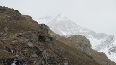 Backdrop-of-Winter-covered-mountains,-foreground-of-jagged-rock-slope