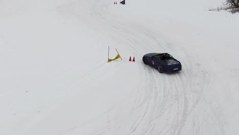 Convertible-car-drifting-on-snowy-winter-race-track,-controlled-slide-in-turns