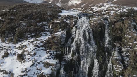 Toma-Aérea-De-Una-Cascada-Nevada-En-Escocia,-En-Cascada-Entre-Rocas-Escarchadas