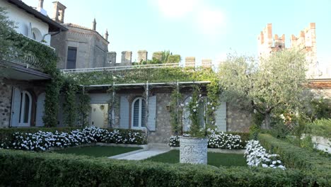 Pretty-manicured-garden-with-white-flowered-borders-and-Sirmione-castle-backdrop