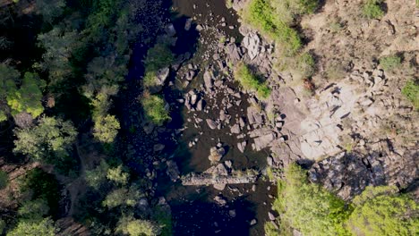 Drone-descends-to-Jundula-river-gorge-boulders,-rocky-terrain-natural-landscape-TOP-DOWN