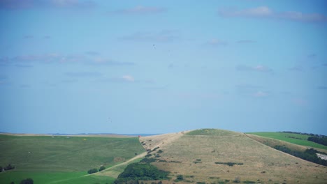 Paragliders-on-the-South-Downs,-Sussex,-under-Blue-Skies