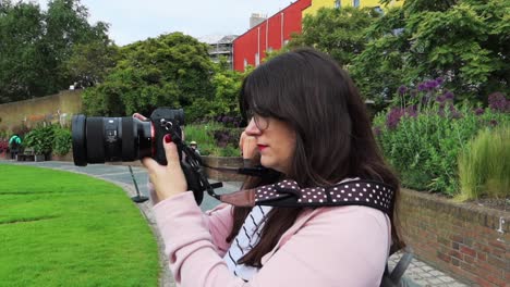 Woman-with-glasses-using-a-DSLR-camera-outdoors
