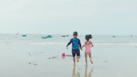 Two-barefoot-children-running-on-the-sand-at-a-beautiful-beach