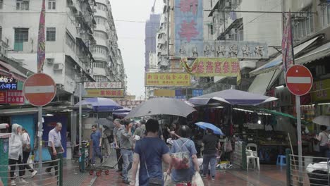 Mong-Kok-area-of-Hong-Kong-street-market-filled-with-vendors-and-pedestrians-with-umbrellas-during-a-rainy-day---Slow-Motion