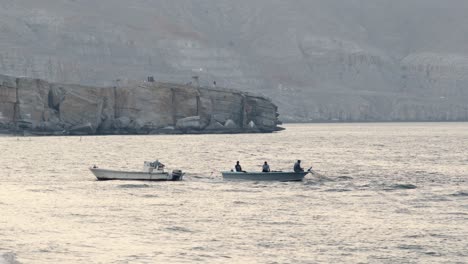 Fishermen-fishing-at-sunset-in-the-blue-sea-of-Khasab,-people-catching-fish-from-the-boat