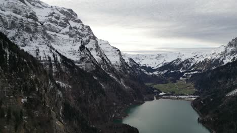 Klöntalersee-Switzerland-Glarus-smooth-aerial-over-lake-in-the-valley-with-village-in-distance