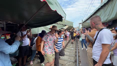 Touristen-Warten-Auf-Den-Zug,-Der-Den-Maeklong-Bahnmarkt-Talad-Rom-Hub-Passiert