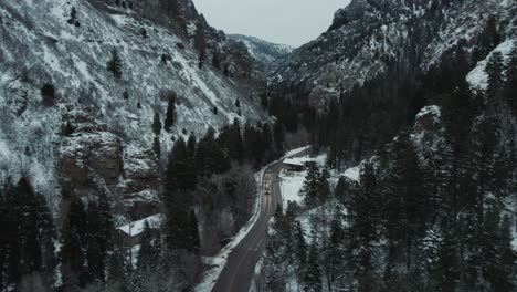 Dramatic-winter-aerial-of-snowy-American-Fork-Canyon-road-near-hillside