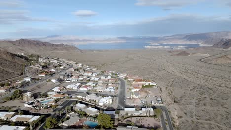 Neighborhood-in-Boulder-City,-Nevada-with-Lake-Mead-in-the-distance-and-drone-video-moving-down