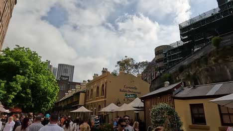 Tourists-and-travelers-roam-across-Rocks-Market-at-midday-under-cloudy-sky,-Sydney-Australia
