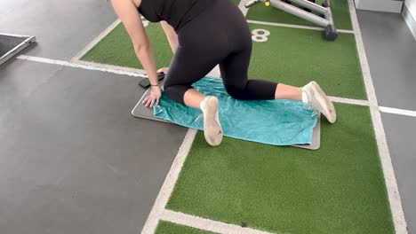 Young-woman-kneels-to-perform-an-exercise-to-work-her-back-in-a-gym