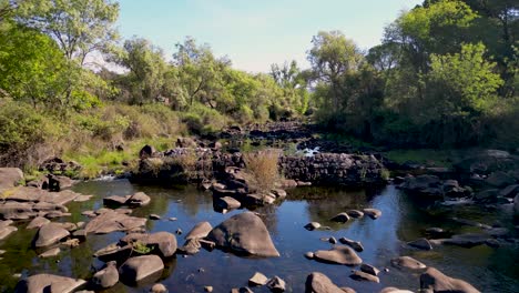 Drone-Sobre-Un-Río-Cubierto-De-Rocas-Sube-Para-Revelar-La-Vista-De-La-Reserva-Natural-De-La-Sierra-De-Andújar