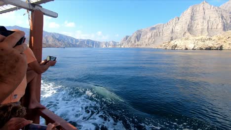 La-Vista-De-Las-Olas-Golpeando-El-Barco-En-El-Mar-De-Khasab,-Los-Turistas-Dando-Un-Paseo-En-Barco-Por-El-Mar-Y-Tomando-Fotos-Con-Sus-Teléfonos