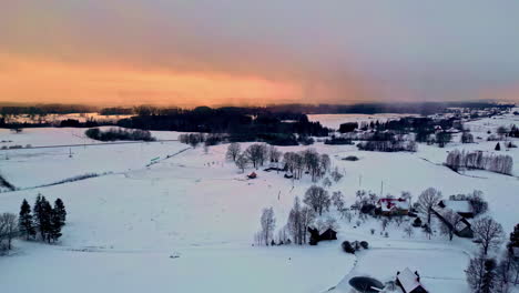 Wide-drone-shot-of-rural-countryside-covered-in-snow-at-sunset