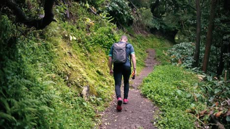 Sportsman-rearview-trekking-a-track-trail-through-mountains-walking-by-muddy-paths-after-rain-amidst-nature-in-the-middle-of-the-forest-and-jungle