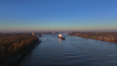 Aerial-dolley-view-of-two-large-vessels-sailing-over-a-dutch-river-during-a-colorful-sunrise