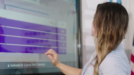 moving-shot-of-a-blonde-female-teacher-teaching-her-students-with-a-big-touch-screen