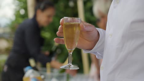 Disparo-Bokeh-Lento-De-Un-Hombre-Sosteniendo-Una-Copa-De-Champán-En-Una-Recepción-De-Boda