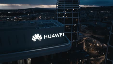 Vista-Aérea-De-Drones-Del-Logotipo-De-Huawei-En-La-Parte-Superior-Del-Edificio-De-Negocios-Por-La-Noche---Primer-Plano