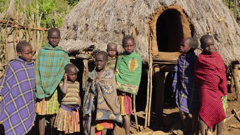 Retrato-En-Cámara-Lenta-De-Una-Familia-De-Niños-Tribales-Parados-Junto-A-Una-Cabaña-En-Uganda,-áfrica