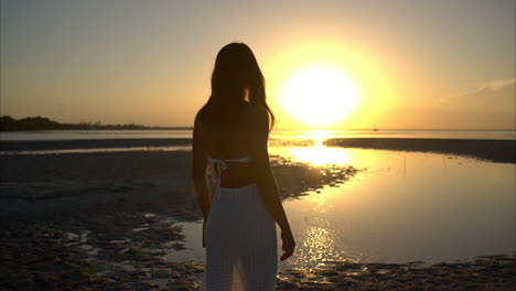 Zeitlupe-Einer-Lateinamerikanischen-Brünetten-Mit-Weißem-Kleid-Und-Sonnenbrille,-Die-An-Einem-Warmen-Nachmittag-An-Einem-Strand-In-Mexiko-Den-Sonnenuntergang-Genießt