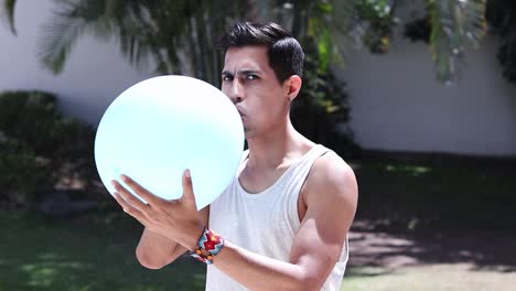 Latino-man-blowing-up-balloon-in-street-at-day-time