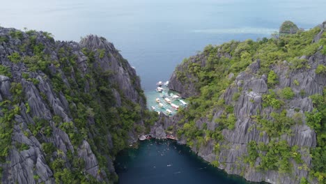 Tour-boats-and-snorkelers-at-Barracuda-Lake-in-Coron,-Aerial-reveal