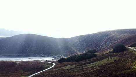 Luftaufnahme-Einer-Drohne,-Die-In-Richtung-Der-Wicklow-Mountains-In-Richtung-Lough-Nahanagan-Fliegt,-Während-Die-Sonnenstrahlen-Durch-Die-Wolken-Scheinen,-Dublin,-Irland