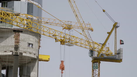 Watching-a-skyscraper-in-progress,-rising-to-a-height-of-at-least-100-meters,-with-vibrant-yellow-cranes-diligently-at-work-on-this-remarkable-structure