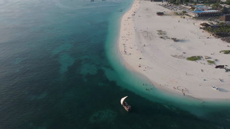 Aerial-view-of-wooden-boat-sails-near-the-wonderful-beach-of-Zanzibar,-shot-at-30-fps