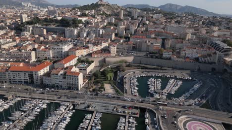 Aerial-View-of-Marseille,-France,-Cityscape,-Traffic-on-Coastal-Road,-Promenade-and-Marina-in-Old-City-Port