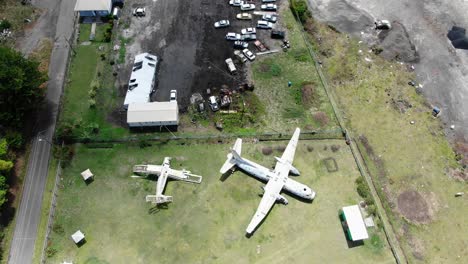 Abandoned-planes-at-pearls-airport-in-grenada,-overgrown-with-vegetation,-aerial-view