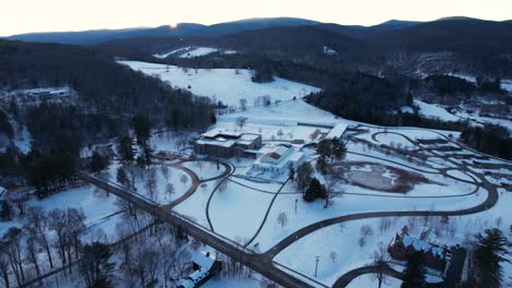 Sunset-over-snow-blanketed-hill-sheltering-a-museum-and-arts-complex-among-forests-of-hardwoods-and-evergreens