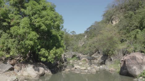 Dorfbewohner-Schwimmen-In-Einem-Kleinen-Staudamm-Im-Fluss,-Umgeben-Von-Vielen-Felsen-Und-Laubbäumen-In-Honduras