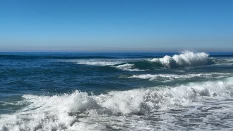 Olas-Del-Océano-Rompiendo-Y-Rociando-Juntas-Durante-La-Marea-Real-Sobre-El-Océano-Azul-Y-El-Cielo-Azul