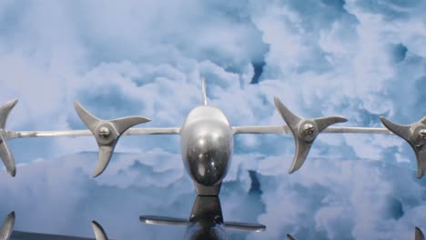 Macro-lens-view-of-silver-model-airplane-with-clouds-in-the-background-and-video-pulling-back