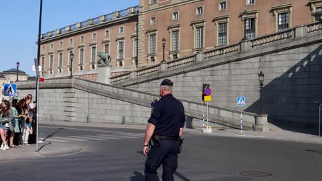 Swedish-police-officer-standing-guard-before-royal-event-at-Stockholm-Palace,-clear-day