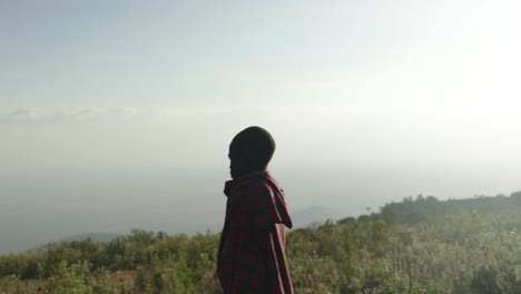 A-young-tribal-African-boy-in-traditional-wear-looks-out-over-the-horizon-in-East-Africa