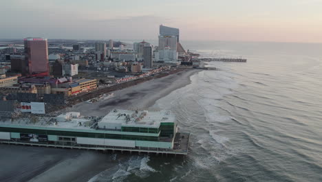 Drone-Volando-Hacia-Atrás-A-Lo-Largo-De-La-Costa-Atlántica-De-La-Ciudad-Mostrando-Hoteles-Casino-Bally-Y-Hard-Rock