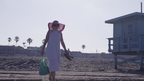 Middle-aged-white-woman-walking-on-the-beach-in-Venice-Beach,-California