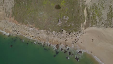 Luftaufnahme-Von-Oben-Nach-Unten-Der-Ruhigen-Meereswellen,-Die-An-Der-Felsigen-Küste-In-Nazare,-Portugal,-Brechen