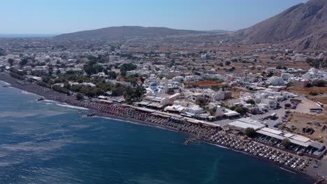 Aerial-Approaching-to-Perissa-Seaside-Village,-Santorini